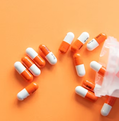 Close-up of orange and white capsules arranged on an orange background